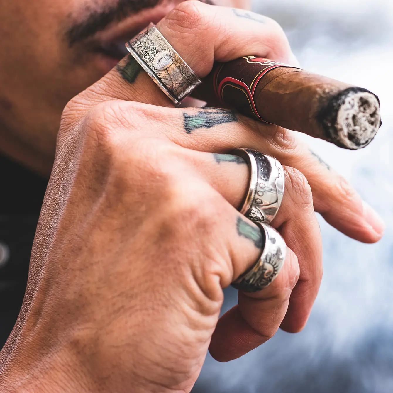 Man smoking cigar wearing multiple rings