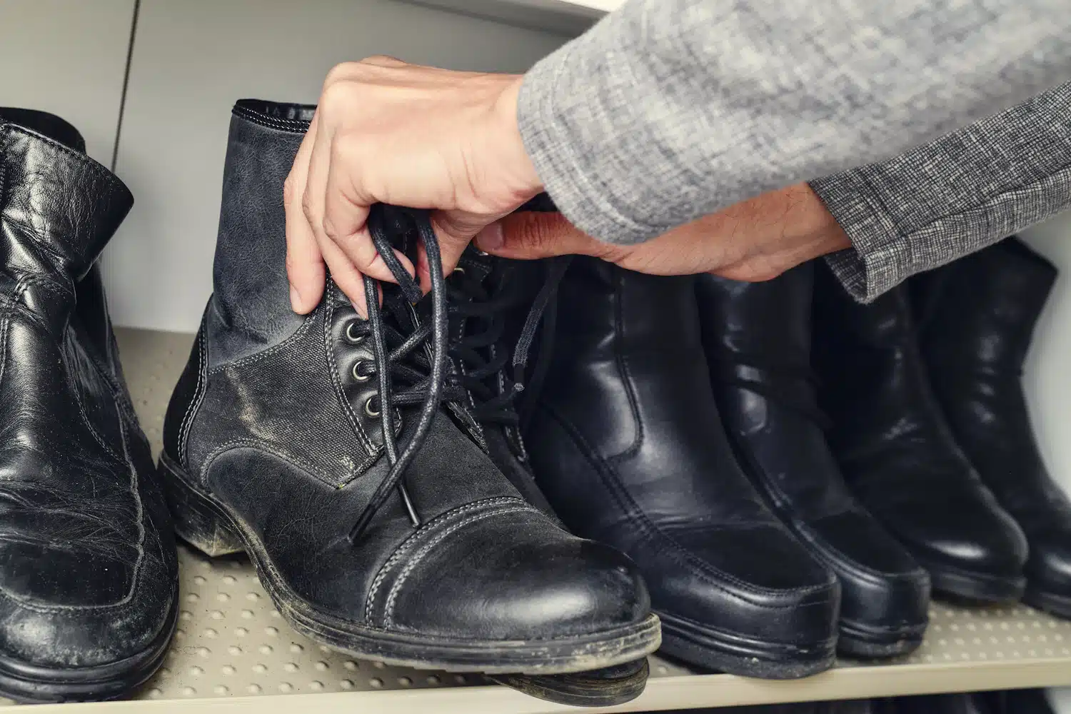 young man picking a pair of boots from the closet