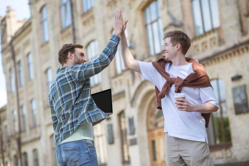 Two men high fiving outside and smiling as they reach their new year goals.