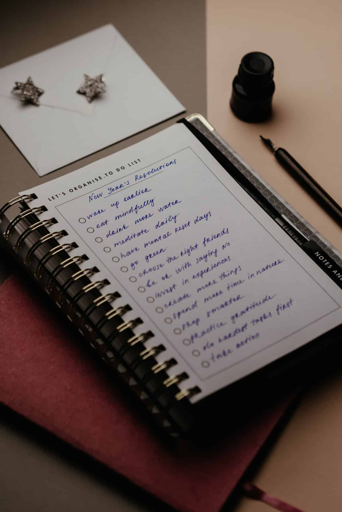 White notebook on a table with a list of New Year's resolutions written in blue ink