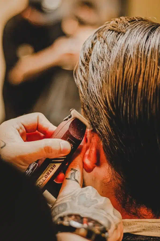 Close up of barber trimming man's hair into fade with long hair hairstyle.