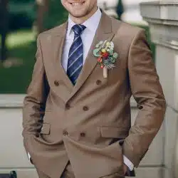 A close-up of a man wearing a brown double-breasted suit with a floral boutonniere.