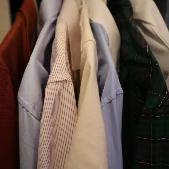 An assortment of dress shirts hanging in a sequence