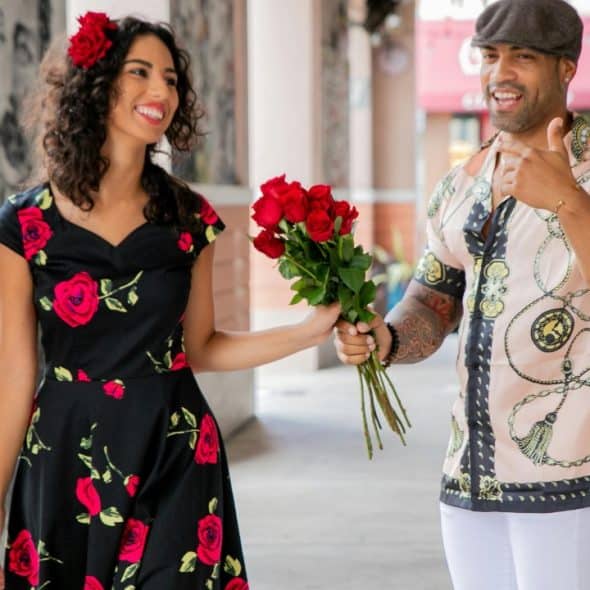 A smiling couple holding a bouquet of flowers.