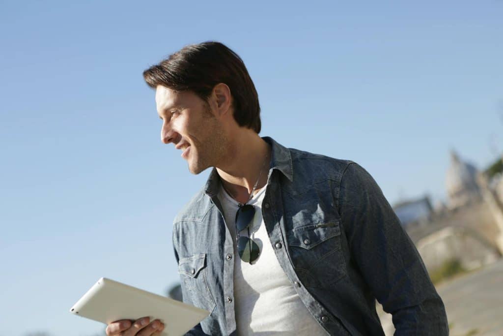 Man in Denim Jacket Holding White Tablet