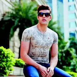 A fit young man in sunglasses wearing a fitted tshirt.