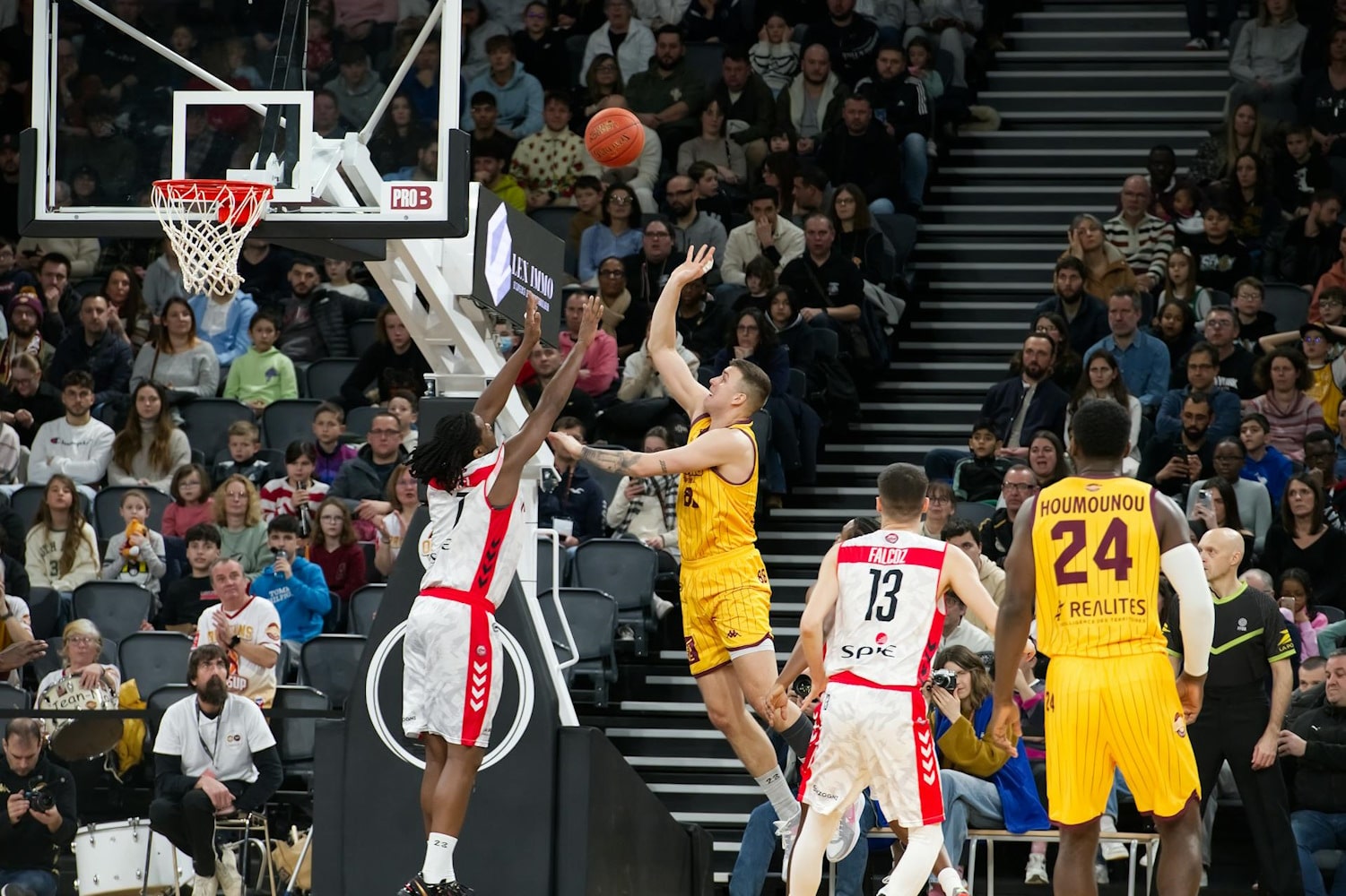 Two basketball players reaching for the ball.