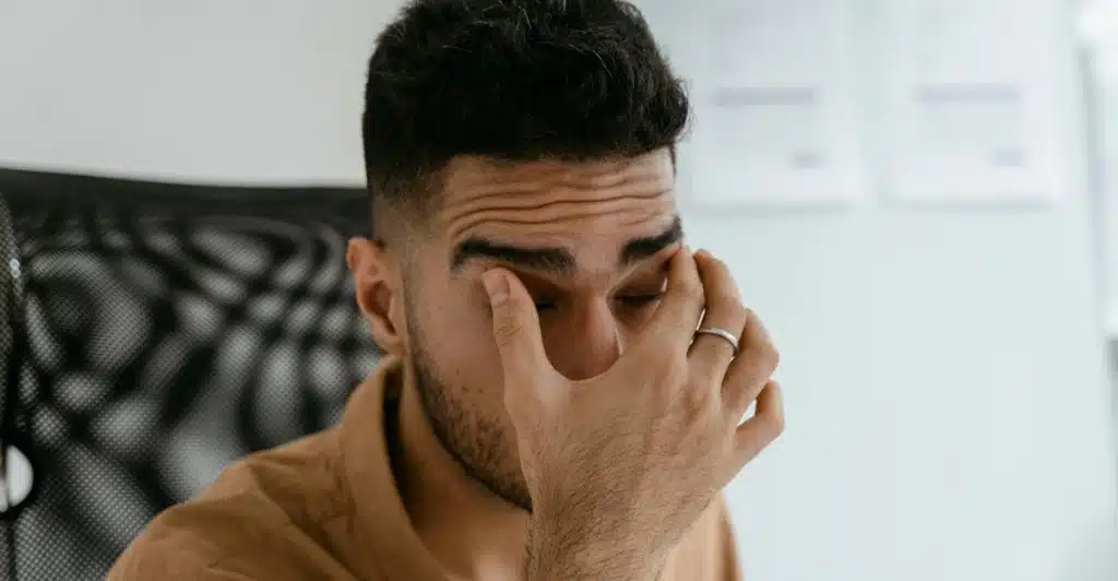 A close-up of a person rubbing their eyes in stress.