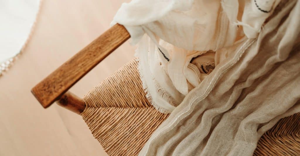 A close-up of a woven chair with soft, draped fabric, showcasing texture and detail.
