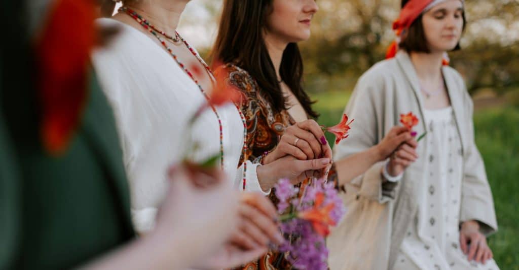  A group of people dressed in traditional clothing, holding flowers, participating in an outdoor gathering.