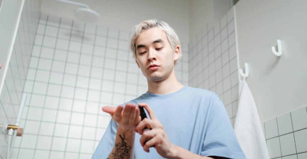 A man applying product to his hands in a bathroom.