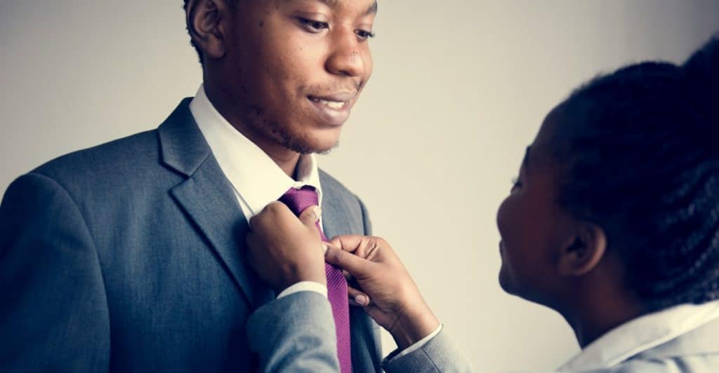 A woman carefully adjusting a man's tie, with the man smiling while looking at the woman .
