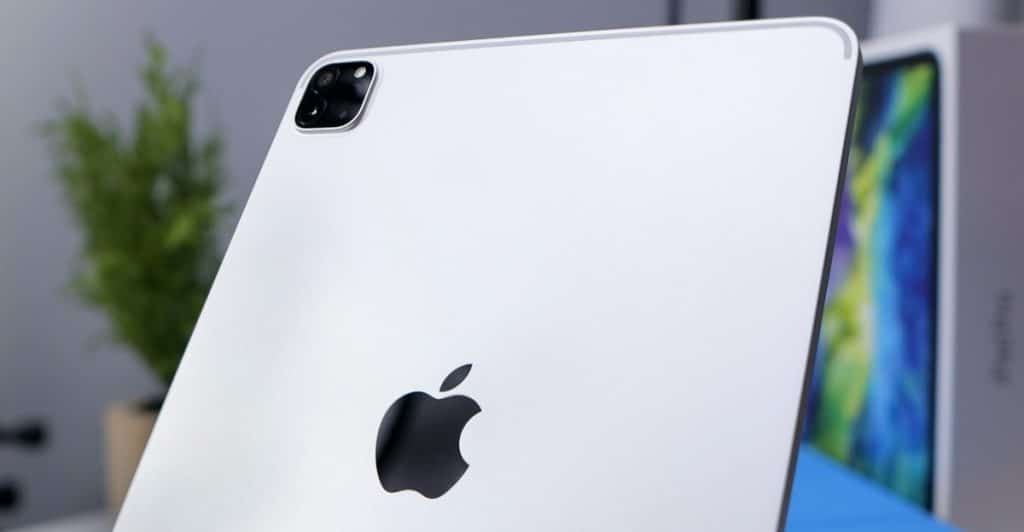  A close-up, angled rear view of a silver Apple iPad Pro, showing the Apple logo and camera module, with a blurred background.