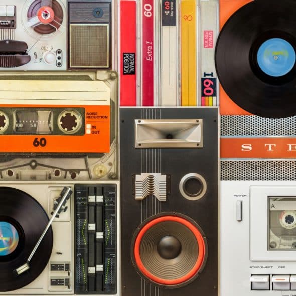 A top-down view of various pieces of vintage music equipment, including cassette tapes, vinyl records, a cassette player, a record player, and a speaker.