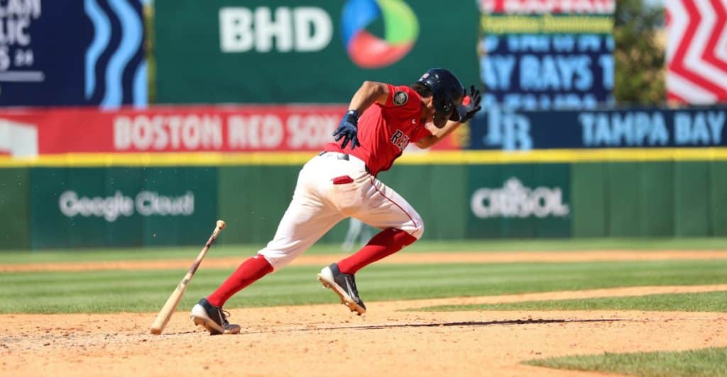 A baseball player wearing a red uniform is running on a field during a game.