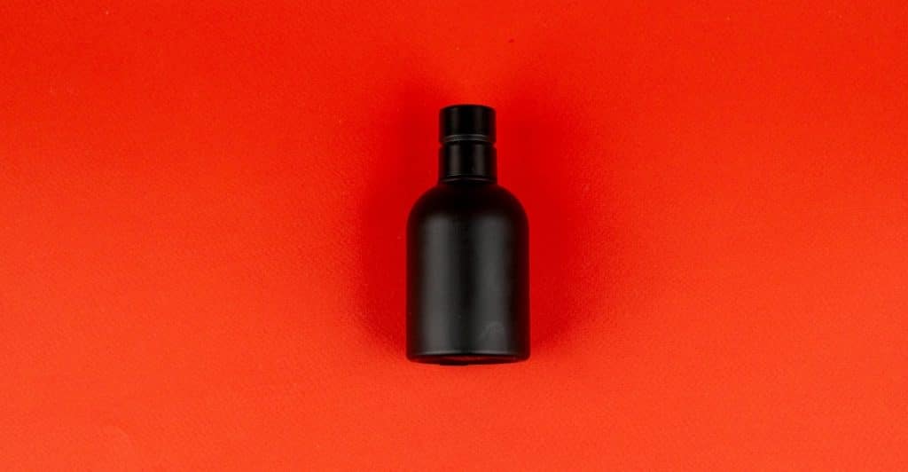 Black Fragrance Bottle Against a Red Background.