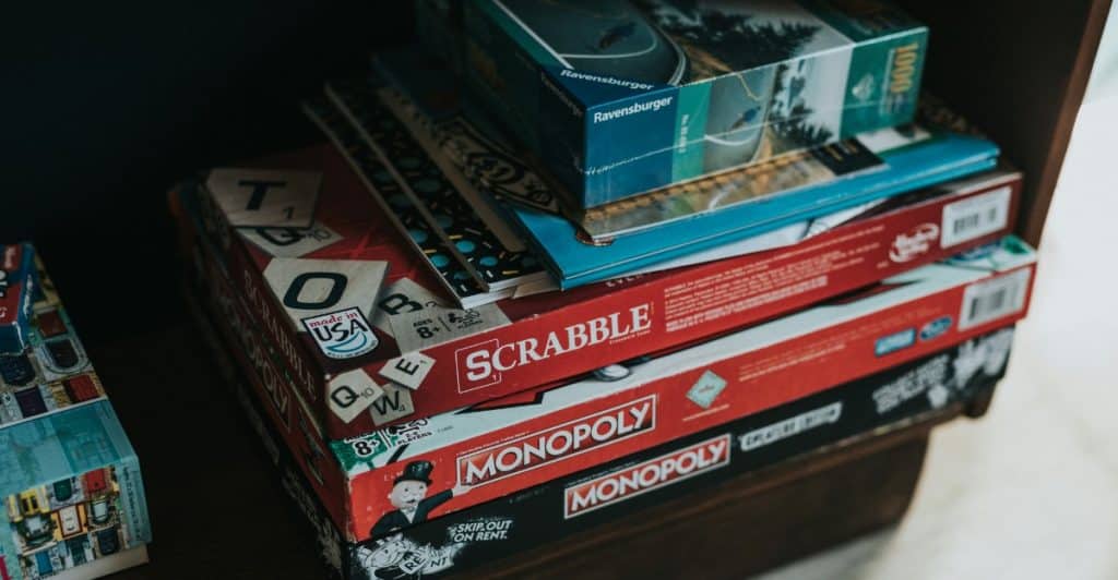 Several board game boxes, including Scrabble and Monopoly, are stacked on a shelf.