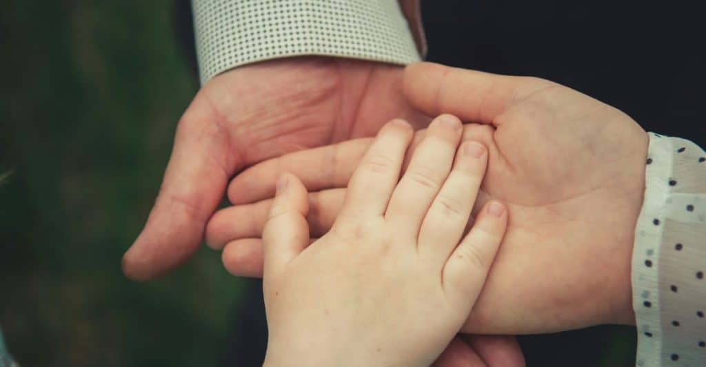A close-up shot of hands of varying sizes on top of each other.