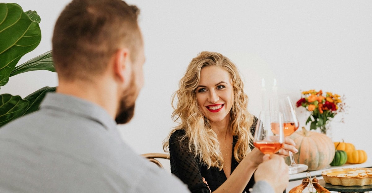 Couple on a date drinking wine with a rotisserie chicken on the table.