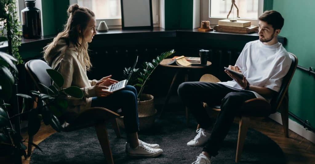 A couple sitting in chairs, facing each other and having a conversation.