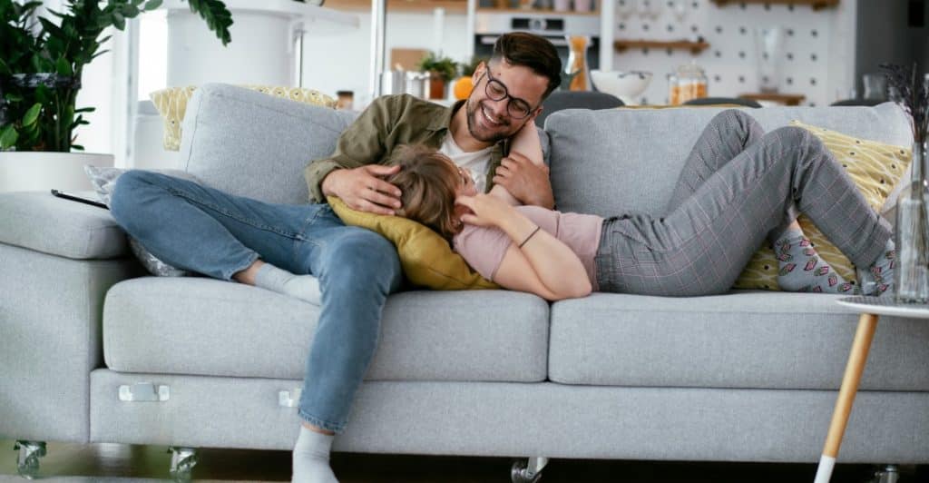 A couple relaxing on a couch, showing intimacy and connection.
