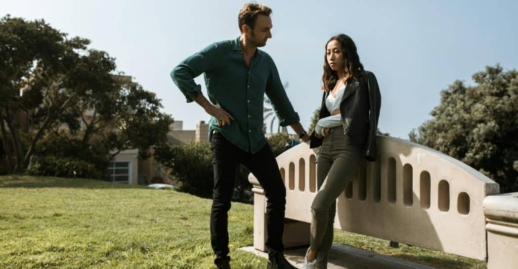 A man and a woman are standing outside, having a conversation.