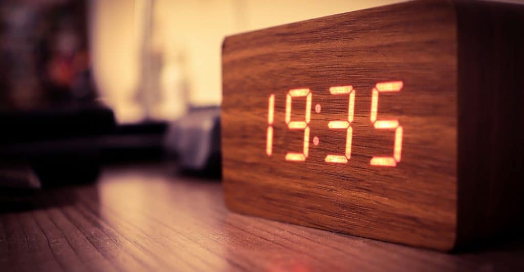 A wooden digital clock displaying the time 19:35 with red numbers.