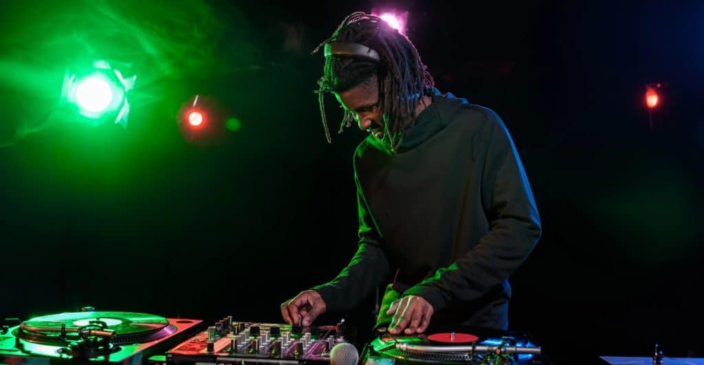 A disk jockey using a sound mixer and turntables during a performance at a nightclub.