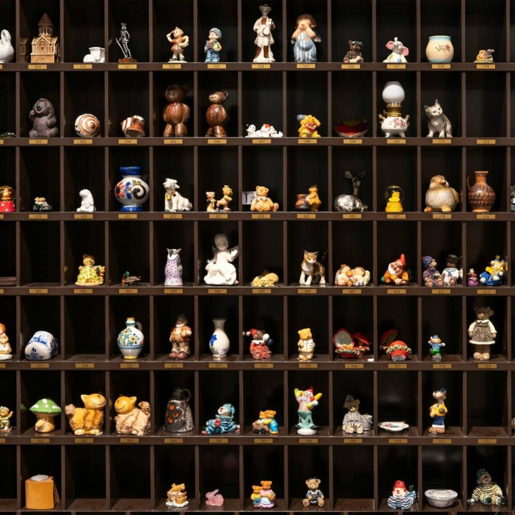A dark brown wooden display case with numerous cubby holes, each containing a variety of small figurines.