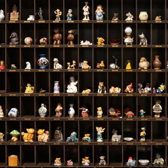 A dark brown wooden display case with numerous cubby holes, each containing a variety of small figurines.