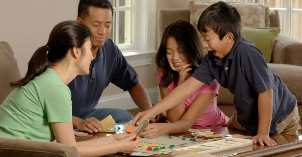 A family of four sitting on a couch, playing a board game.