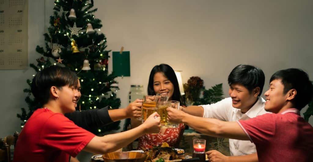 A group of young adults raising their glasses in a toast at a festive dinner table.