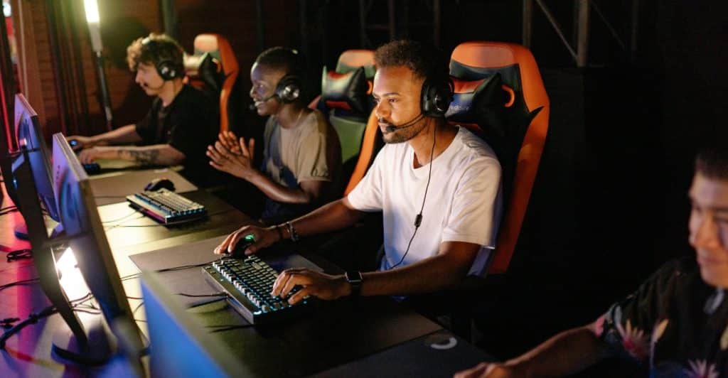 A row of gamers sitting at computer stations with headphones and microphones.