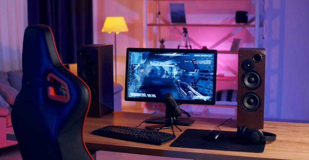 A clean desk with a monitor, smartphone, keyboard, mouse, headphones, flowers, and a drink.