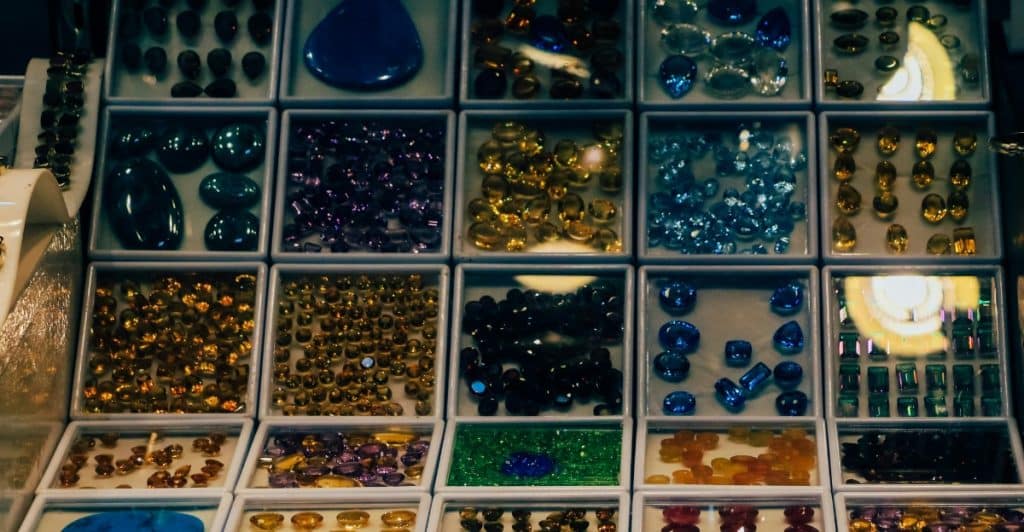 A collection of gemstones arranged in small compartments, displaying a variety of colors and cuts.
