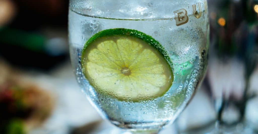  Close-up of a clear glass with a lime slice and condensation.