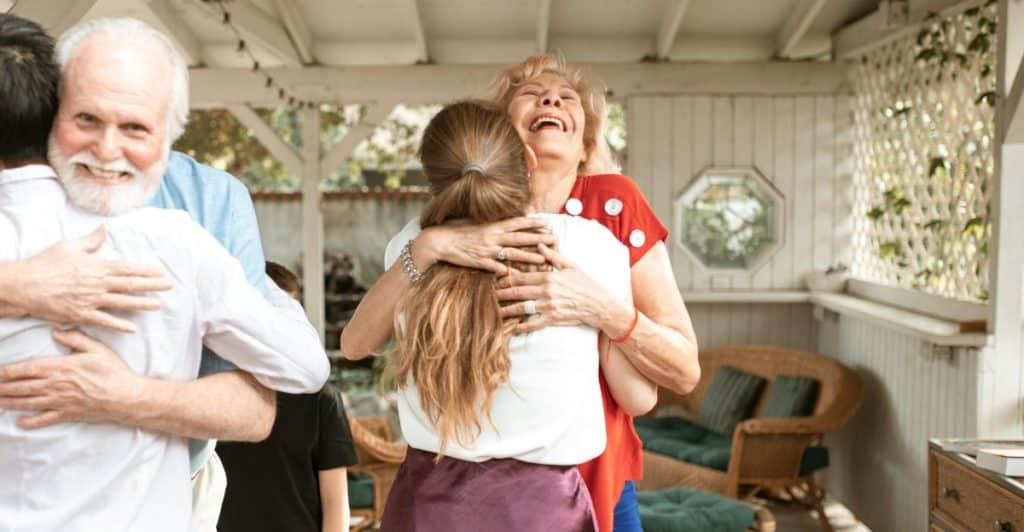 A group of people hugging and greeting each other.