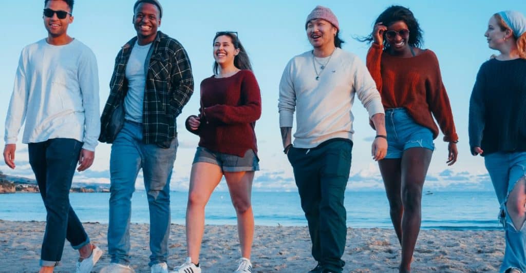 A group of smiling friends walking on the beach.