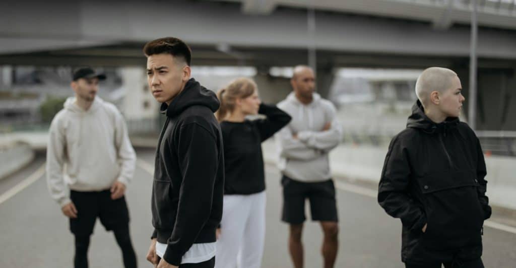 A group of people wearing various colored hoodies are standing on an outdoor walkway.