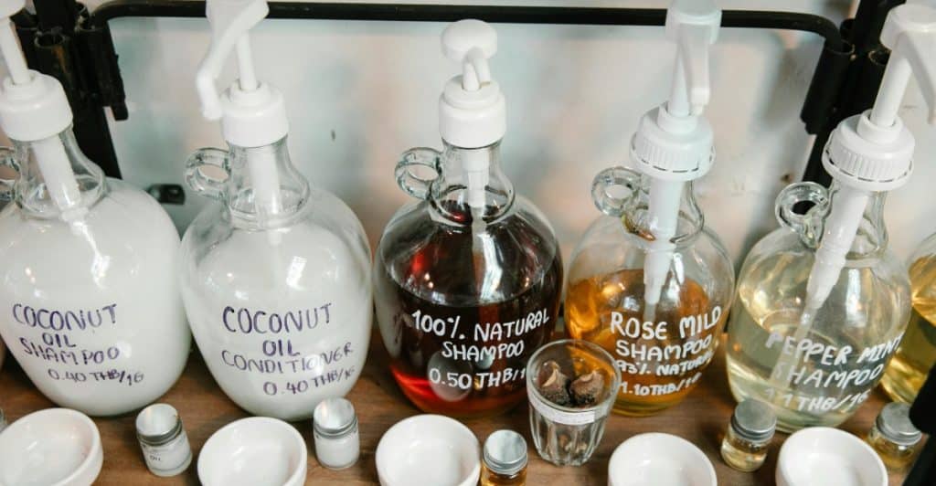 Several glass bottles with labels for various hair products are on a shelf.