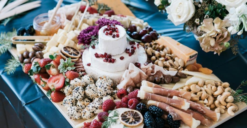 An overhead shot of a charcuterie board filled with a variety of fruits, cheeses, nuts, and meats.