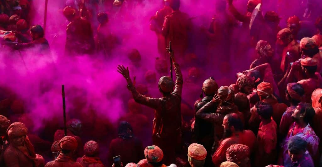 A crowd of people throwing colored powder during the Holi Festival.