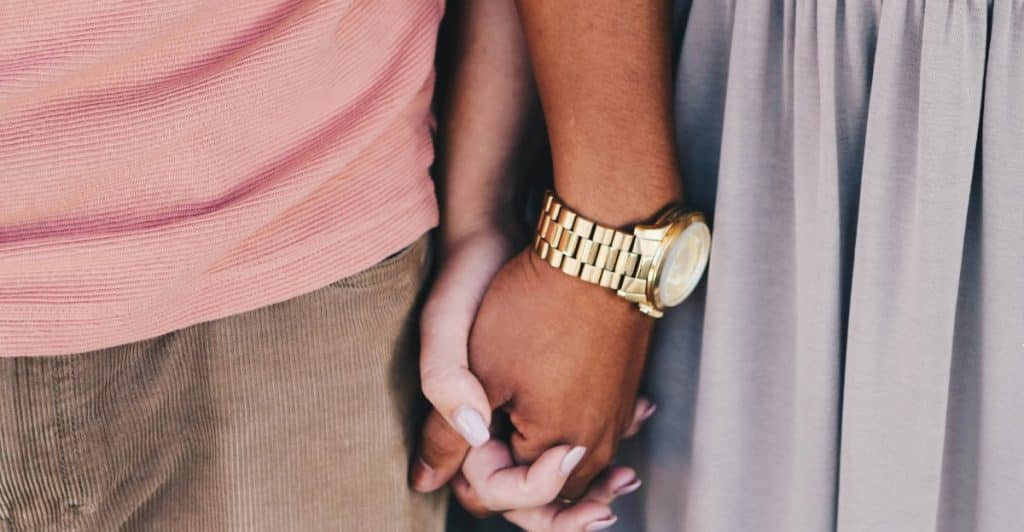 Close-Up of an Interracial couple holding hands.