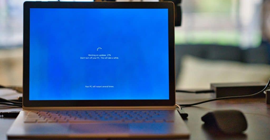 A laptop displaying a blue screen with a progress indicator for an update.
