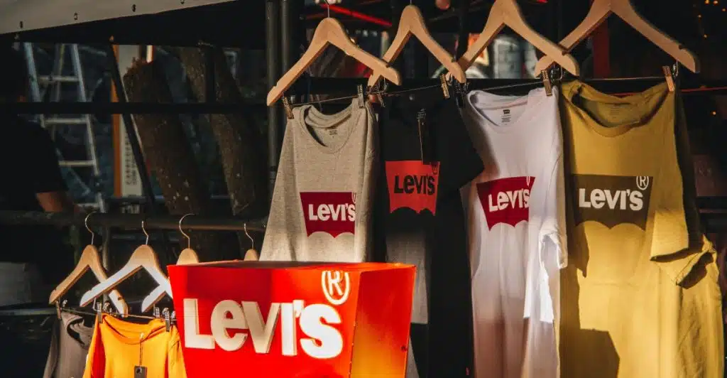 A clothing rack displaying various Levi's t-shirts in different colors, along with a red Levi's branded display bin.