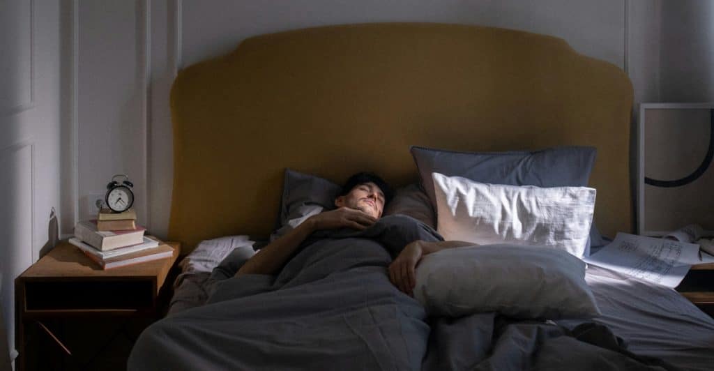 A person relaxing in a bed with pillows.