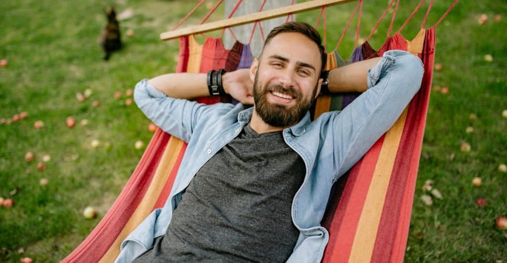 A person smiling while relaxing in a hammock outdoors.