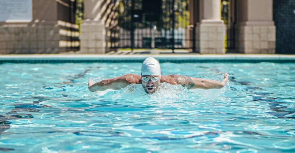 A man swimming butterfly stroke in a pool.