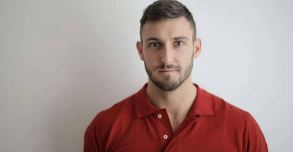 A handsome man wearing a red polo shirt.