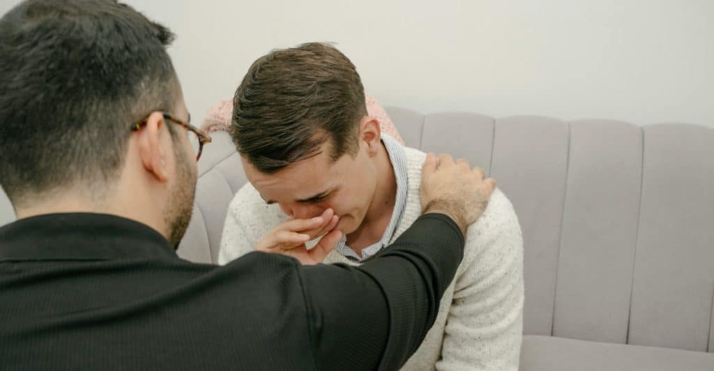 A man being comforted by another person, showing emotional support.